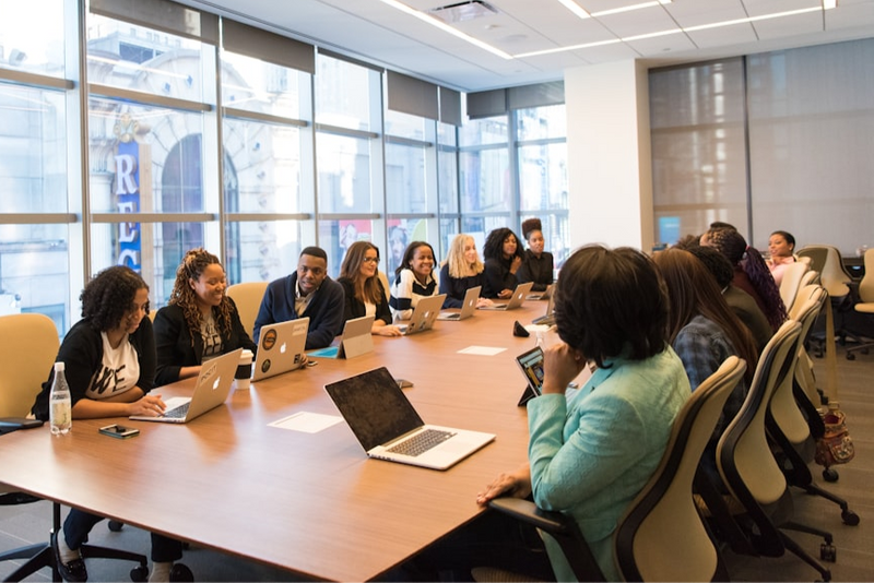 People talking during a meeting at a long boardroom table.