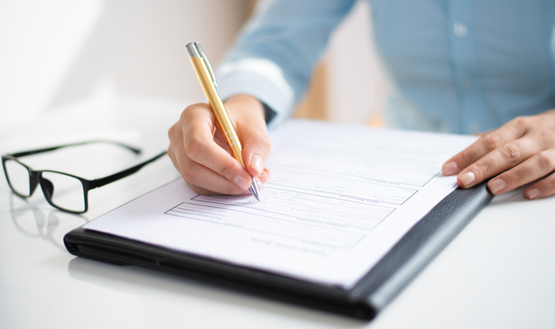 A person in an office writing on a sheet of paper.