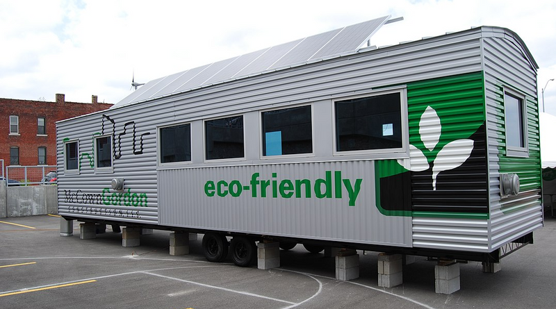 Eco-friendly jobsite trailer includes solar panels, wind turbine, recycled materials, and heat pump technoology.
