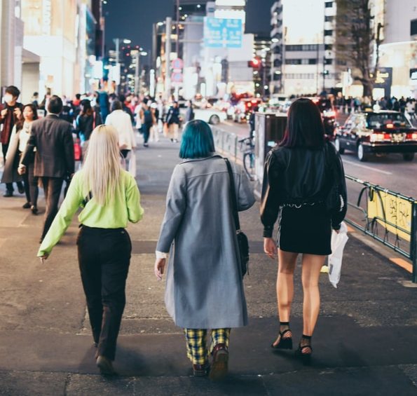Three friends walking down a busy street at night