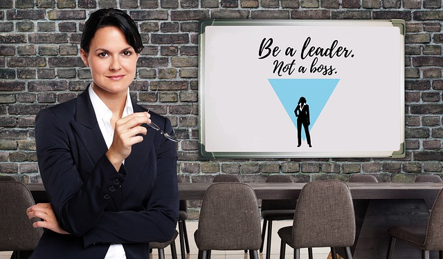A woman in a conference room. On a screen, the text reads, 'Be a leader, not a boss.'