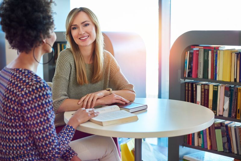 Two women talking at a desk. One woman demonstrates active listening skills.