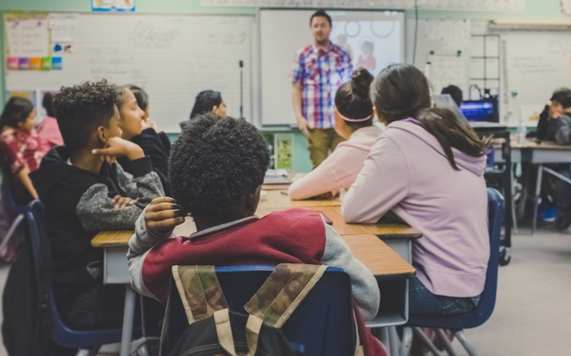 Students in a high school classroom listening to their teacher.