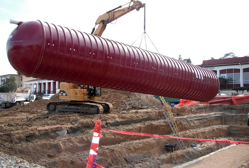 Construction equipment lifting 35,000-gallon tank into place to collect rainwater from a building's roof.