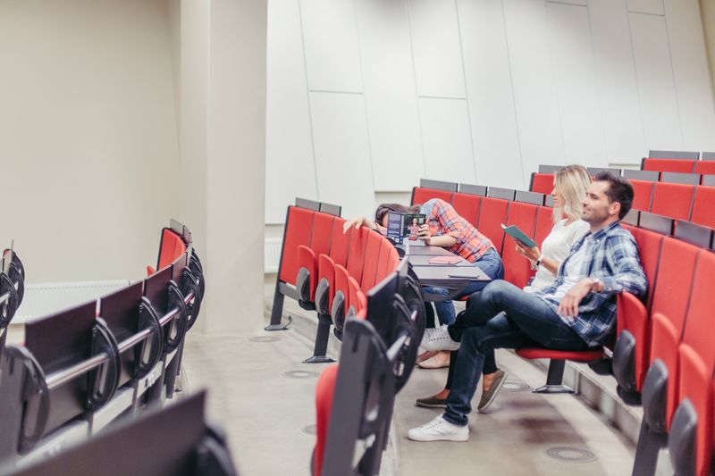 Three bored students sitting in a classroom, not paying attention to the class.