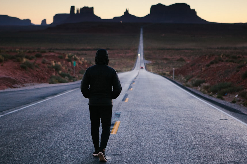 photo of a person walking down a road with a long path ahead.