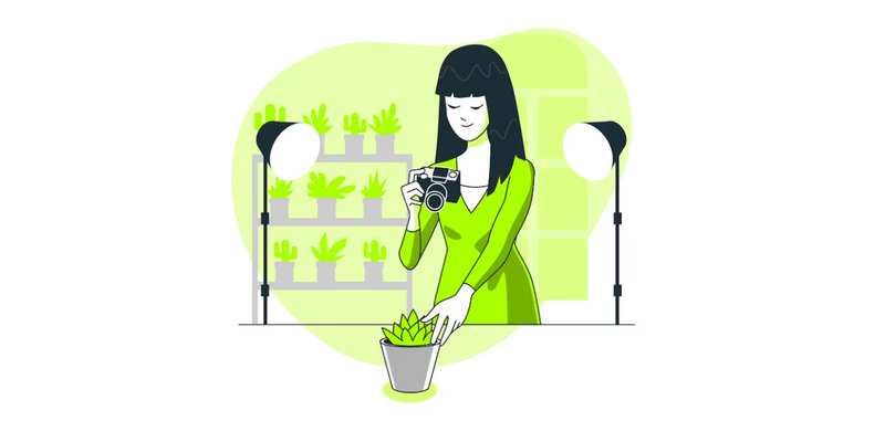 A woman-person with bangs haircut and dress is taking a picture of a plant under two light lamps in a greenhouse.