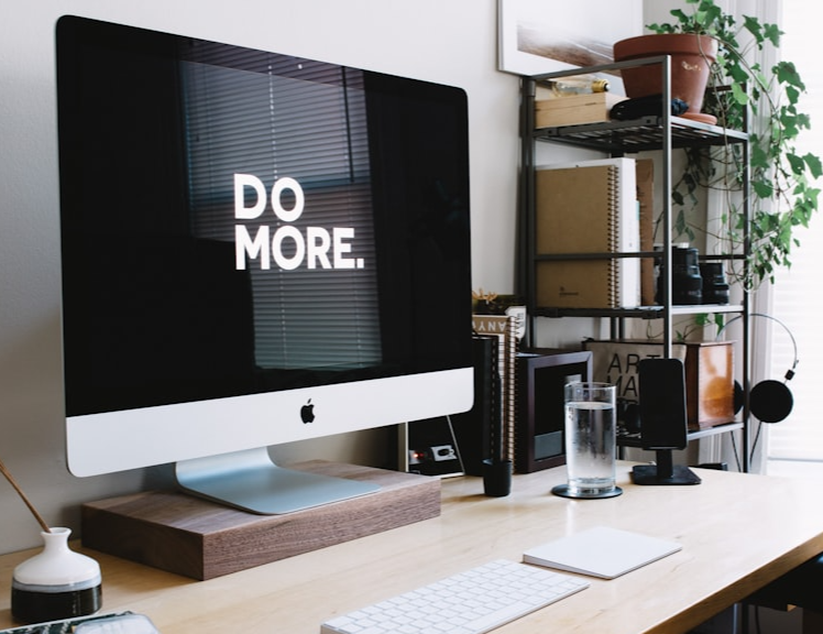 A computer that says 'do more' on screen. The computer is on a desk with office supplies.