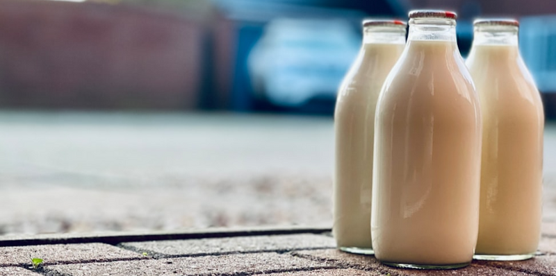 Three glass bottles of milk on the ground.