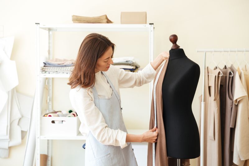 A fashion designer measuring fabric on a mannequin