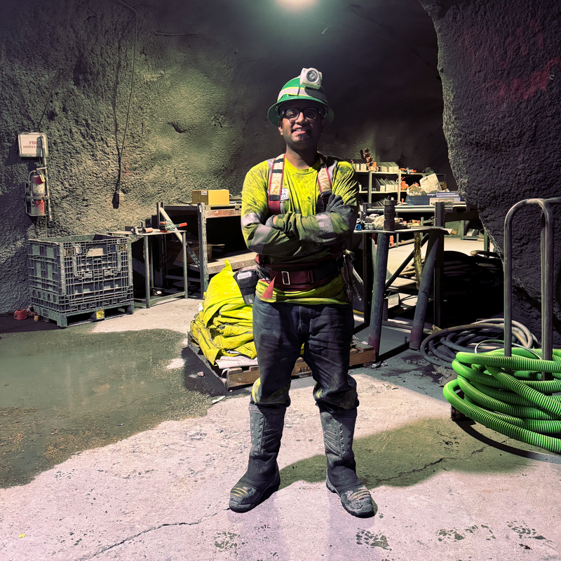 Sai, dressed for the job in his hard hat and safety vest, smiles during an underground shift in the mine.