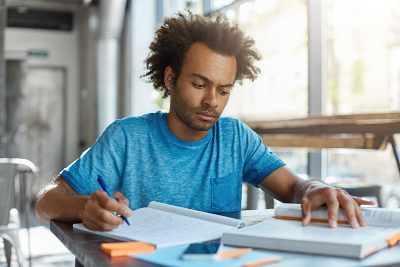 A student looking at a book and taking notes.