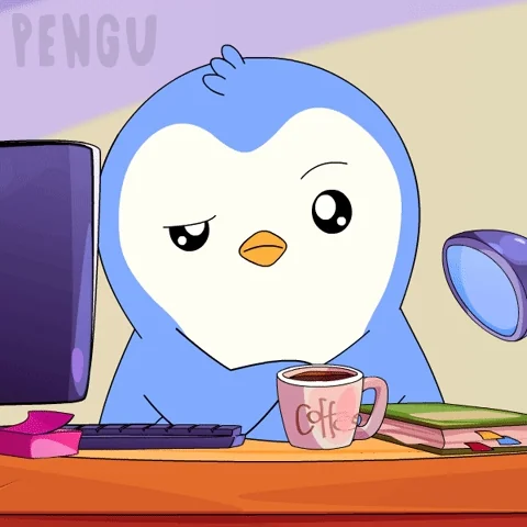 A cartoon penguin sitting at a work desk with a frown and arms folded.