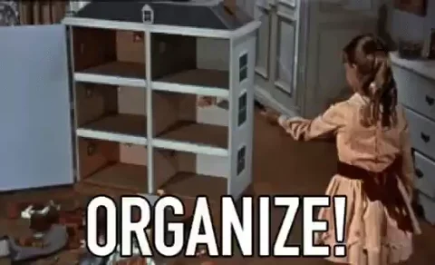 A child pointing to a doll house with the picture showing the word 'organize', and items fly into the dollhouse.