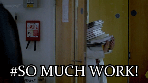 A woman carrying a high stack of books into a room. The text reads, “So much work!”