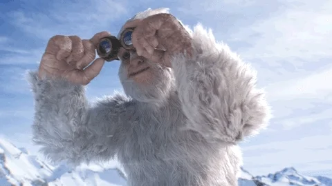 a large white abominable snowman putting on round glasses in the winter snow and mountains
