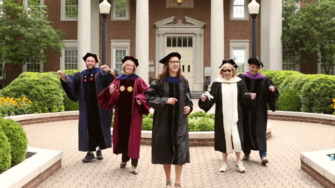 University professors in gowns dancing on campus