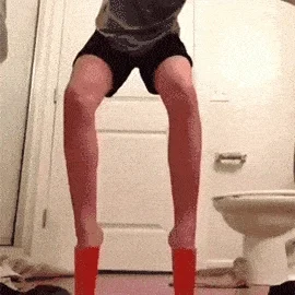 A child doing ballet in a bathroom. They use plastic cups on their feet for ballet shoes.