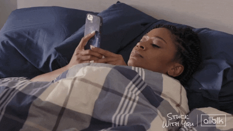 person lying in bed looking at their phone