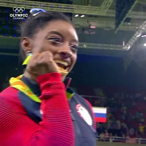 Gymnast, Simone Biles, bites on Olympic gold medal