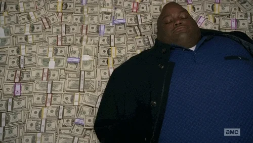 A man relaxes on a giant bed of money.