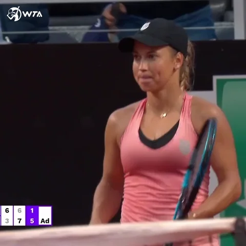 A tennis player brushes off her shoulders after winning a point.