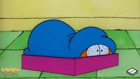 Garfield the cat wakes up tired, rubs his eyes, and pulls the blanket back over his head.