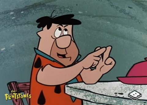 Fred Flinstone counting on his fingers and looking confused.