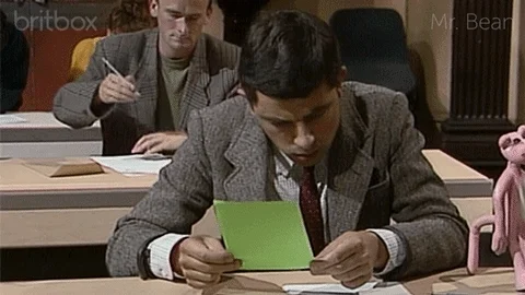Mr. Bean looking at an exam paper and panicking.