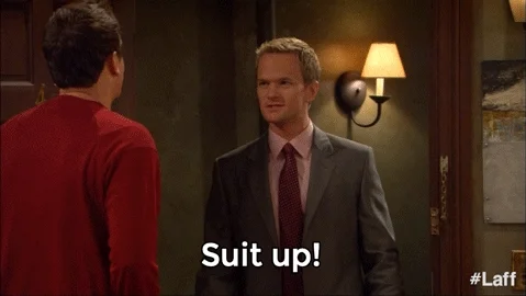 Barney from How I Met Your Mother, dressed in a suit, saying to another man, 'Suit up!'