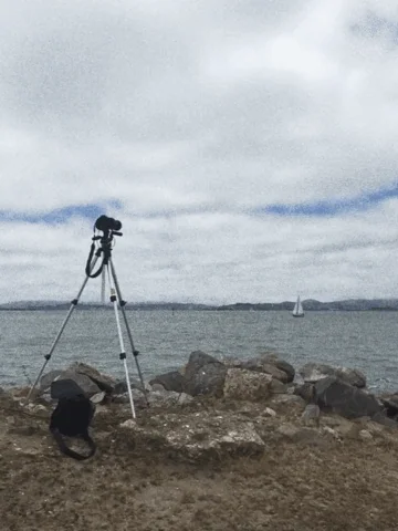 A camera on a tripod in front of a lake.