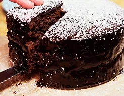 A person serves a slice of chocolate cake.