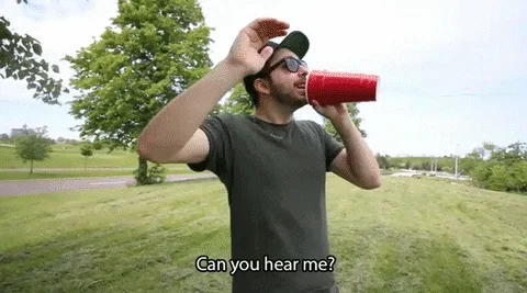 Two people cant hear each other as they try to speak through a plastic cup phone.