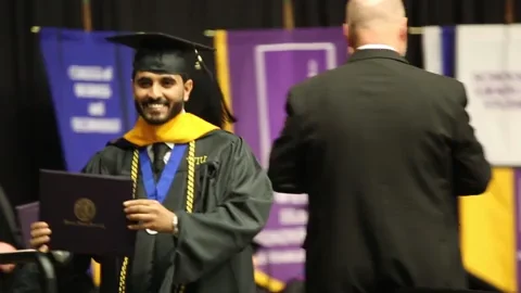 A student holding their diploma as they graduate.
