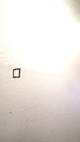 Man stands behind a clear barrier and uses a marker to check a box, then he smiles and nods 