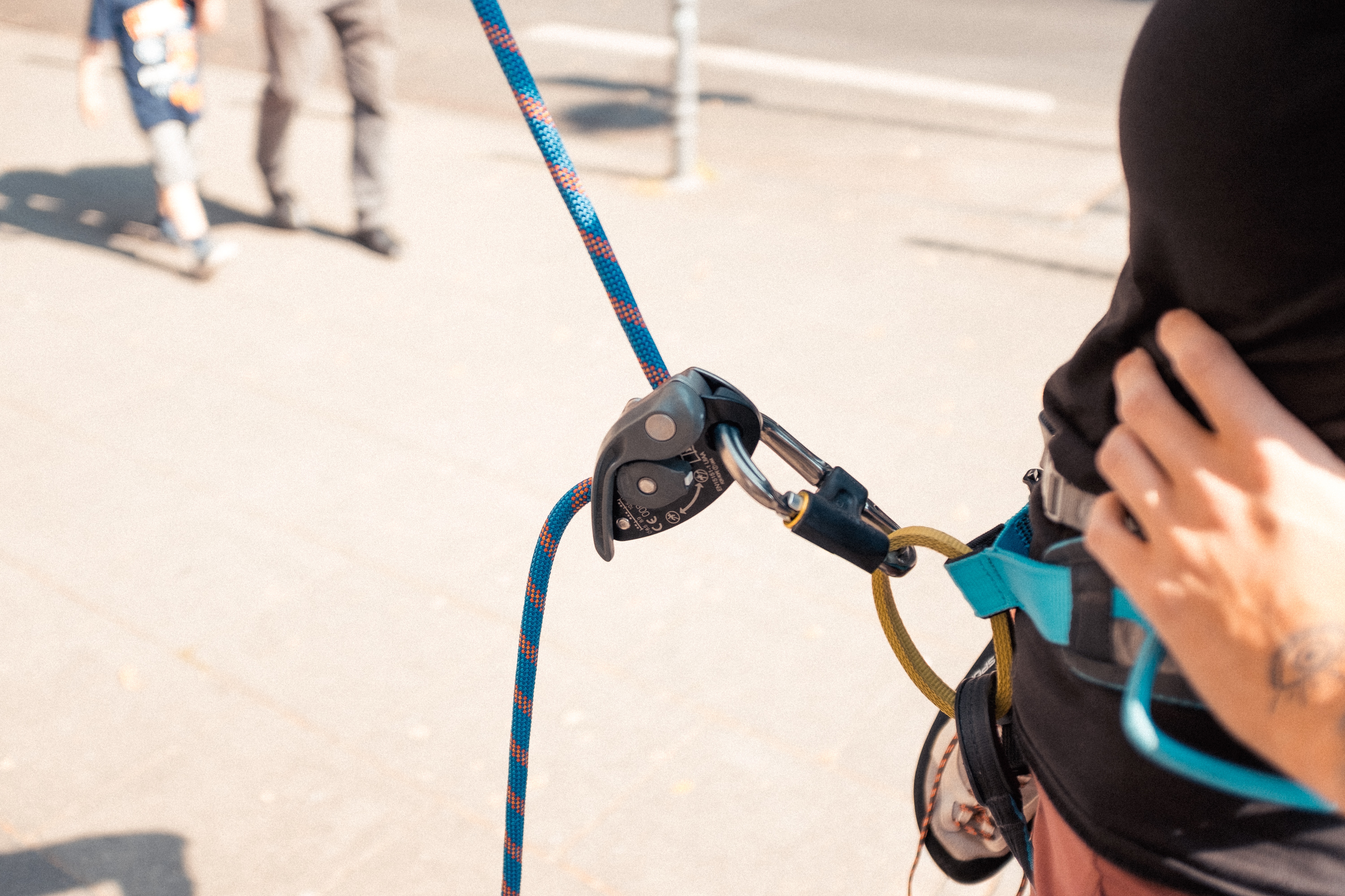 A climber in a harness with a belay device and a rope.