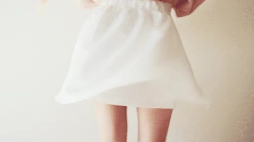 A woman twirling in a white skirt.