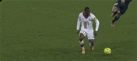 Two football players - one 'nutmegs' the other but passing the ball through the opponent's legs.