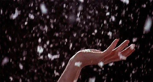 Snow falling on a person's hand.