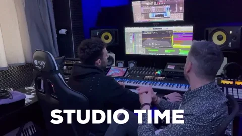 Two producers work together in a home studio. The text reads, 