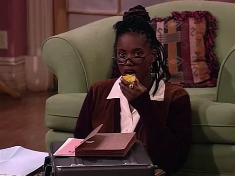 Erika Alexander from 'Living Single' looking around as she eats an apple while studying.