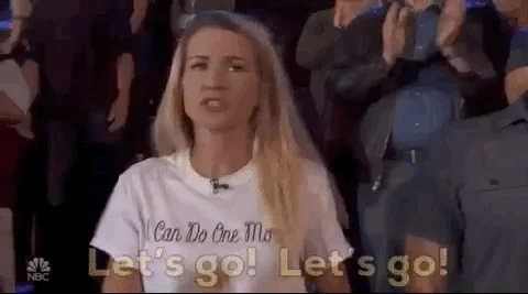 An excited woman in a TV show audience clapping and saying, 'Let's go! Let's go!'