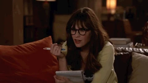 Jess from New Girl gasps with wide eyes and open mouth, reacting to a sudden realization.