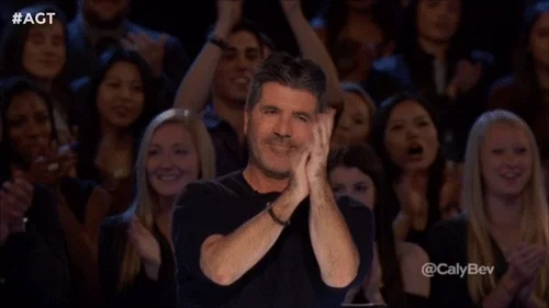 Simon Cowell clapping and giving 2 thumbs up.