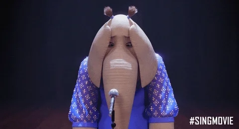An animated elephant looks shy, standing at a microphone.