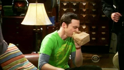 Sheldon from The Big Bang Theory hyperventilates into a paper bag.
