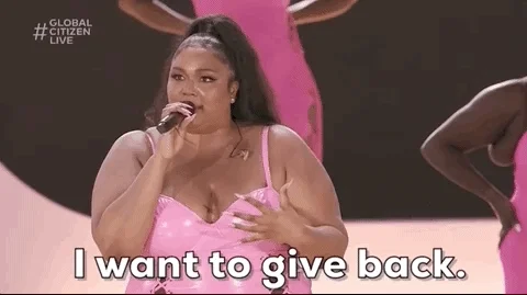 Lizzo on stage in  a pink dress saying ,