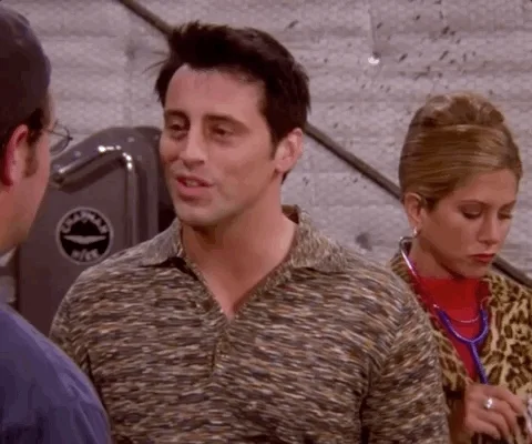 Joey from Friends pulls his earlobe & says, 'You have got to listen,' while a grinning Rachel holds a stethoscope behind him.