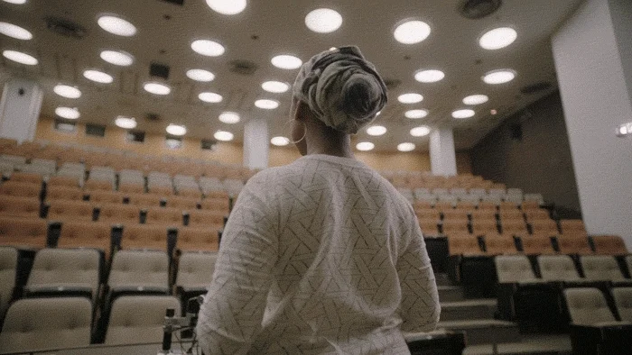 An instructor on her first day of college as a teacher looking around an empty lecture hall.