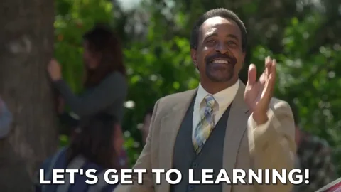 Man in suit smiles and claps hands once with the caption - let's get to learning!